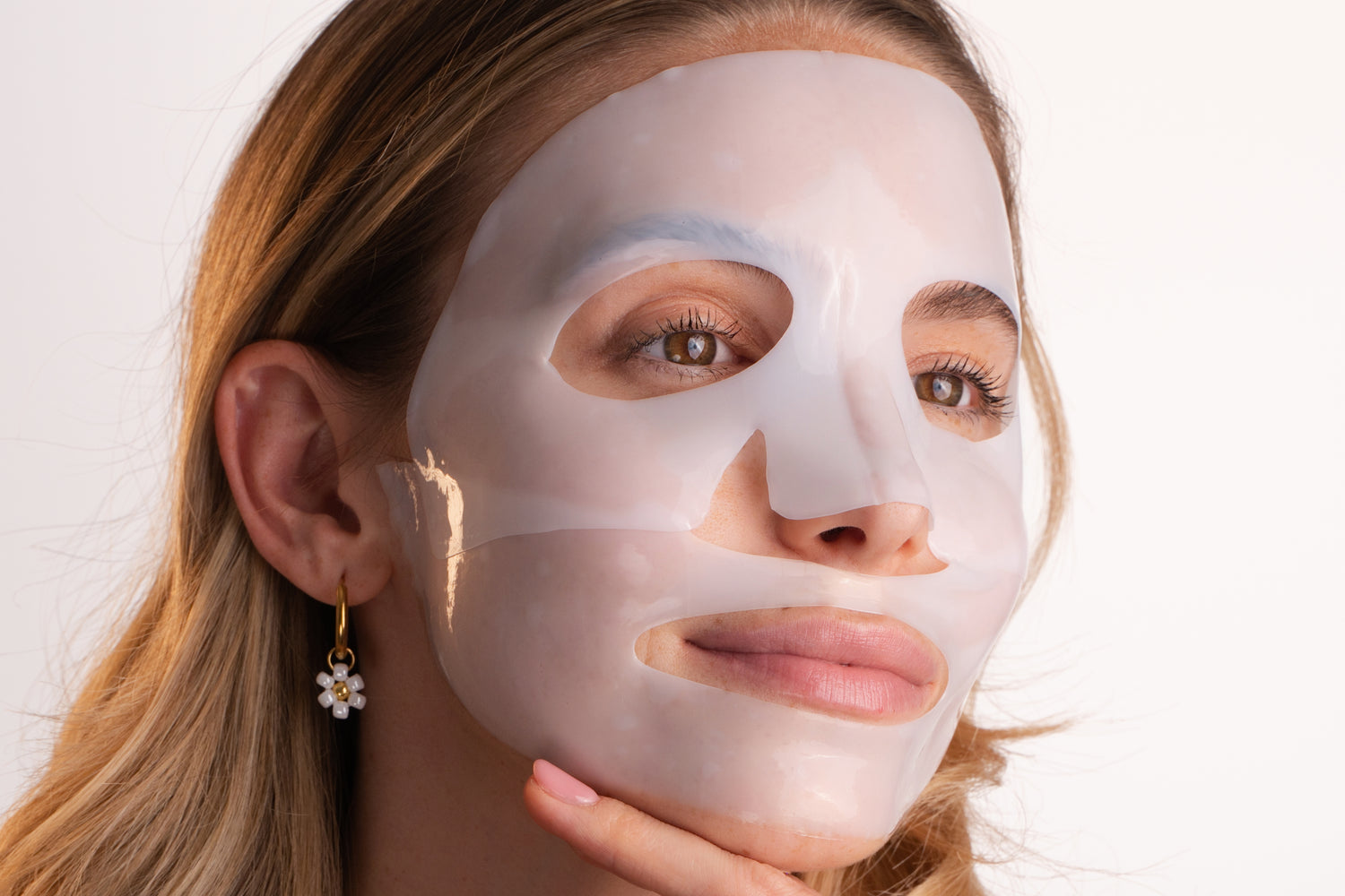 Pem Delian Lumiskin arcmaszk mosolygó modell arcára téve álla alatt tartott kézzel távolba nézve 