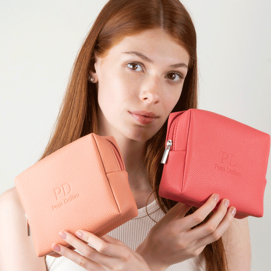 Pem Delian barack és korall színű sminktáska vörös hajú modell kezében