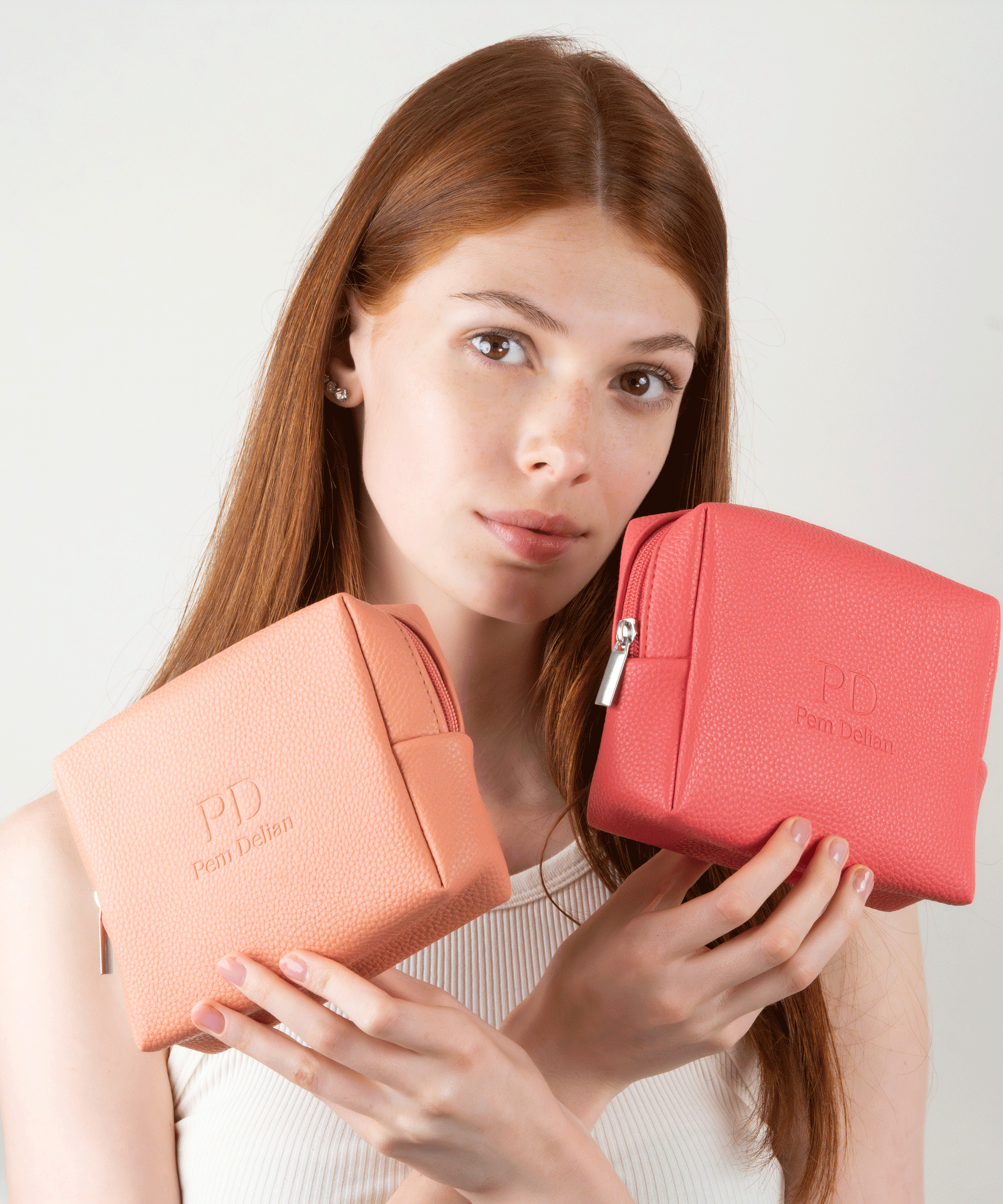 Pem Delian barack és korall színű sminktáska vörös hajú modell kezében