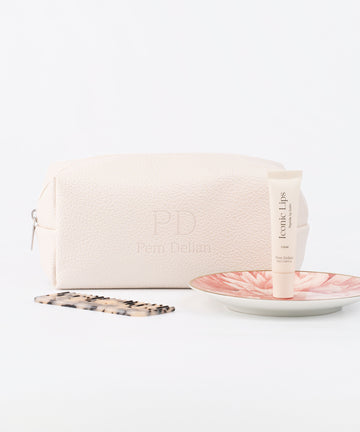 Pem Delian beige vegán bőr neszesszer és Iconic Lips Clear ajakápoló tányéron, mellette fésű