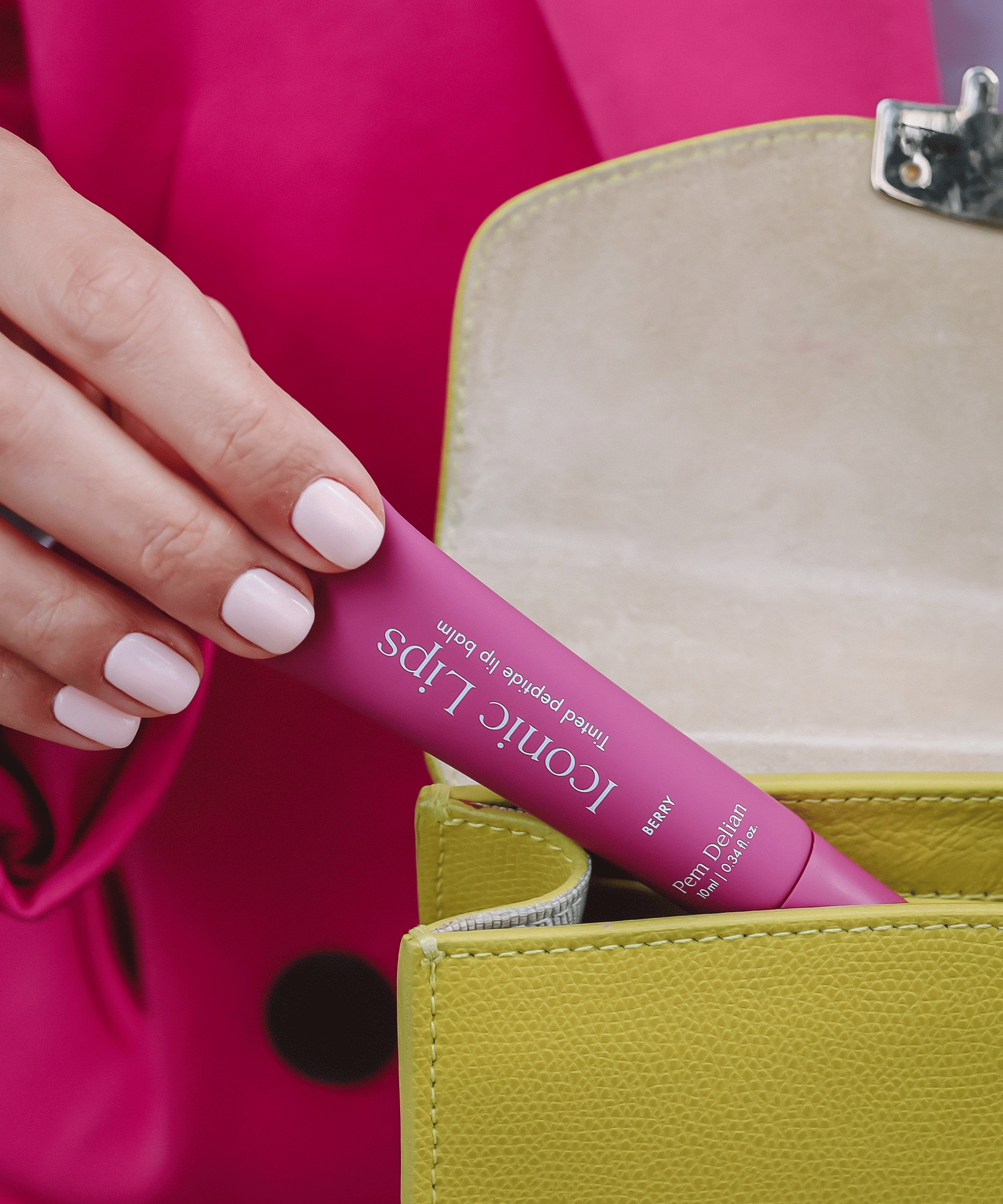 Iconic Lips Berry színezett peptides ajakápoló sárga színű táskából kiemelve , modell kezében