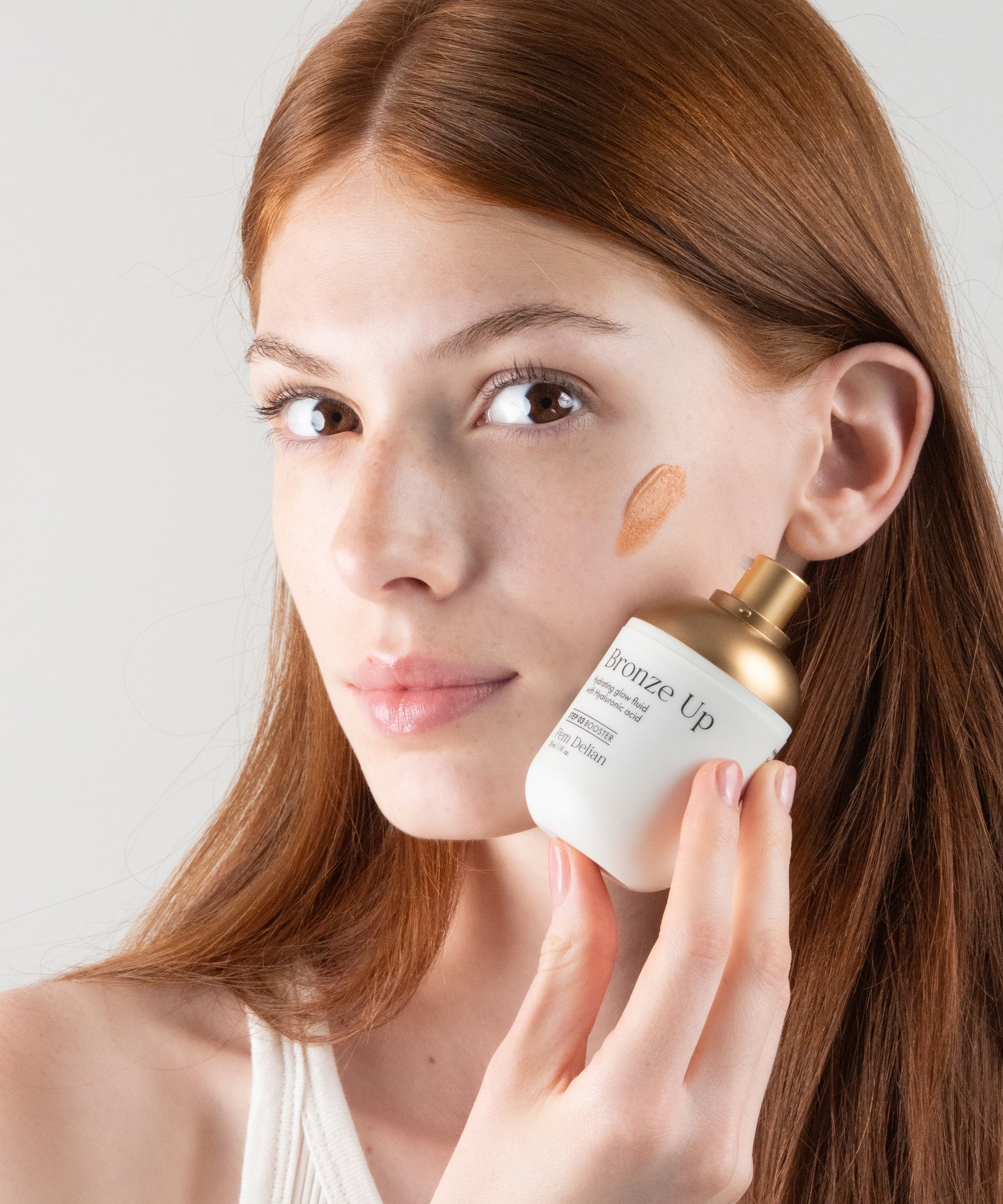 Pem Delian Bronze Up hidratáló, ragyogásfokozó fluid hialuronsavval
vörös hajú modell kezében, textúra kikenve az arcon