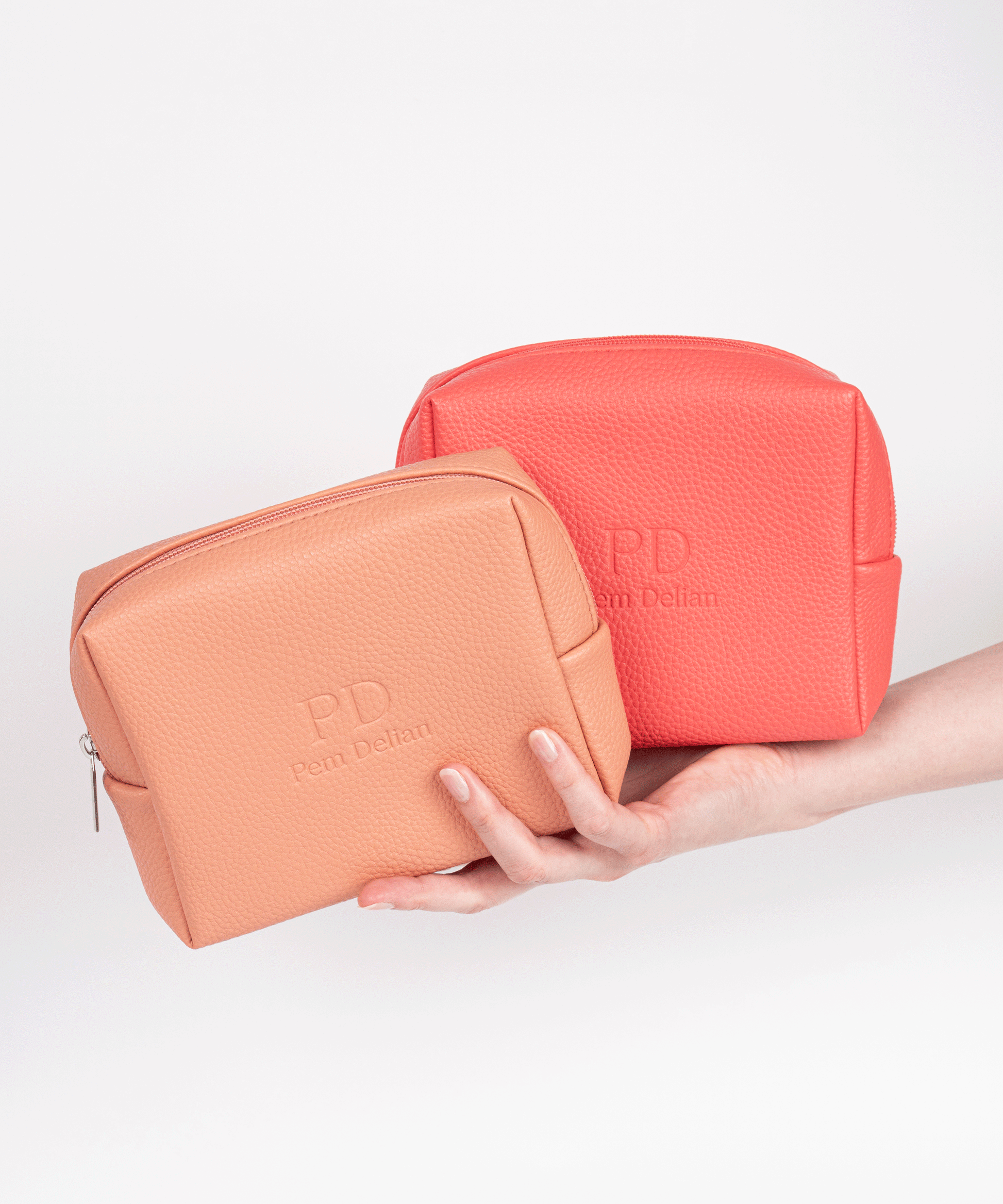 Pem Delian korall és barack színű vegán bőr sminktáska modell kezében