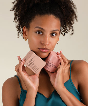 Cosmopolitan anti-aging arckrém tégelye és doboza barna hajú modell kezében.