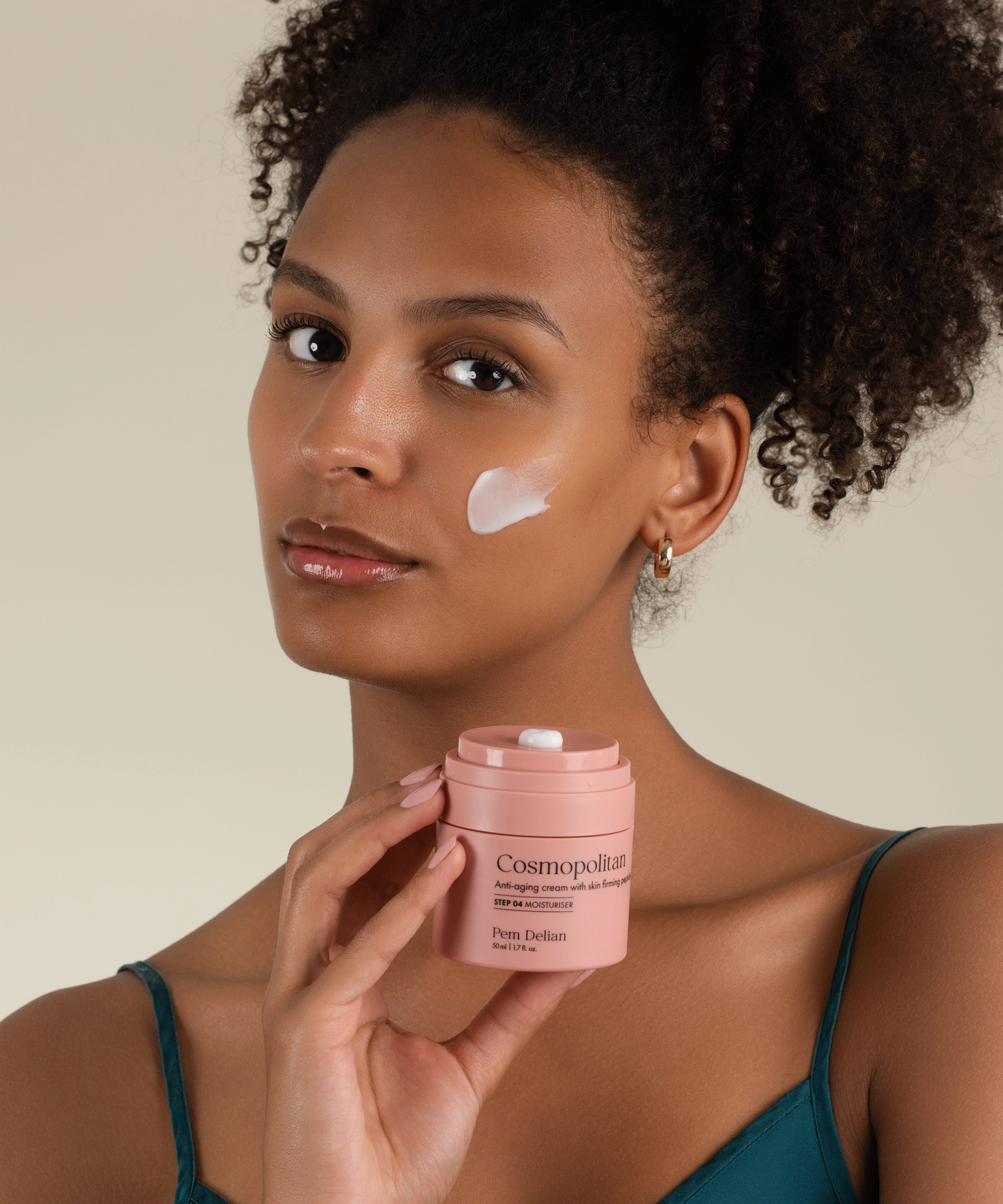 Pem Delian Cosmopolitan arckrém feszesítő peptidekkel a modell arcára kikenve, kezében a termék tégelye