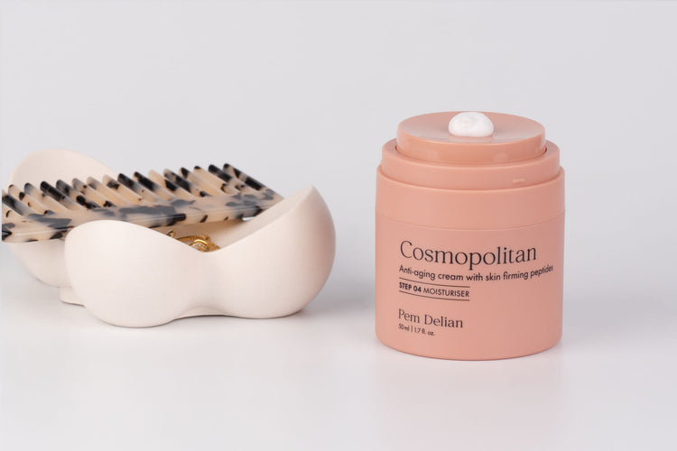 Pem Delian Cosmopolitan anti-aging arckrém tető nélkül, mellette tál, fésűvel, gyűrűvel