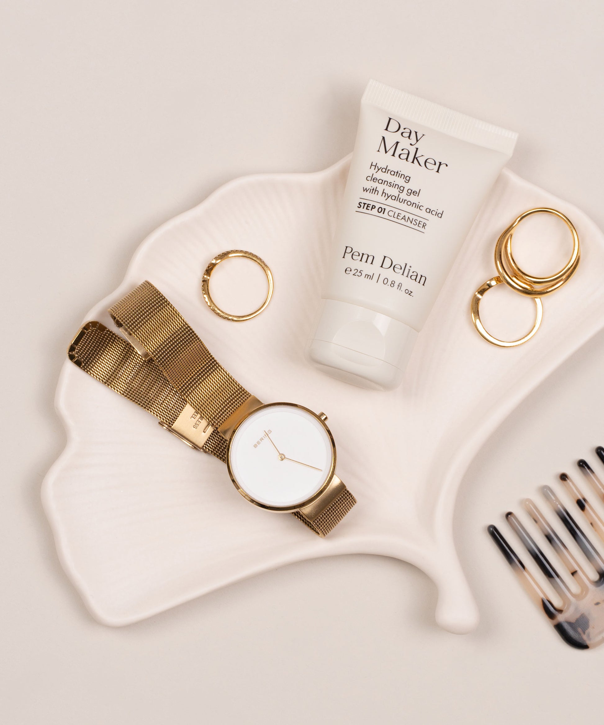 Mini Pem Delian Day Maker Hidratáló arctisztító gél hialuronsavval levél alakú tányéron, mellette gyűrűk, óra és fésű
