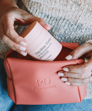 Pem Delian NMF intenzív hidratálókrémet a modell beteszi a korall színű neszesszerbe