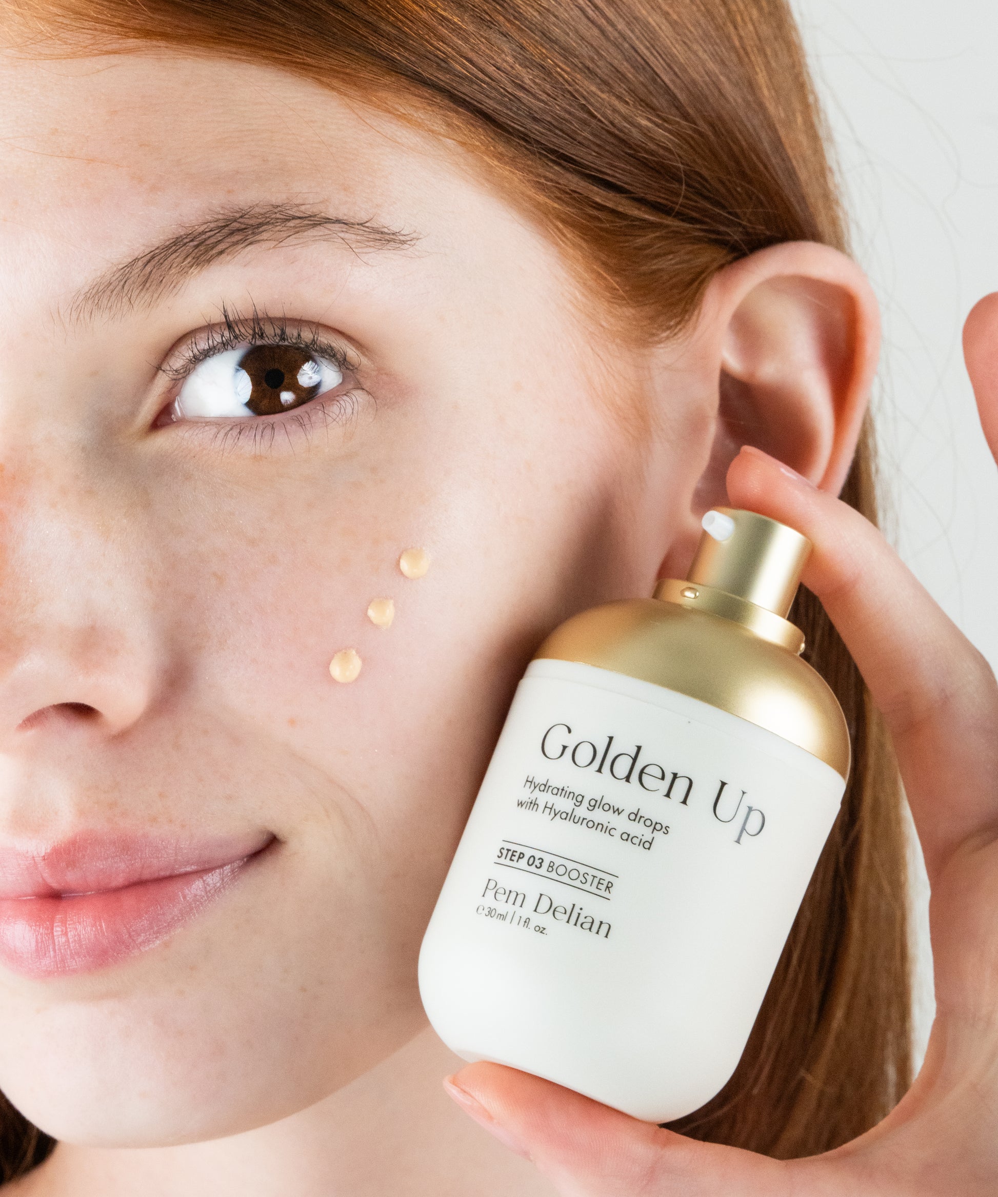Pem Delian Golden Up hidratáló, ragyogásfokozó fluidból 
árom csepp a vörös hajú modell arcán