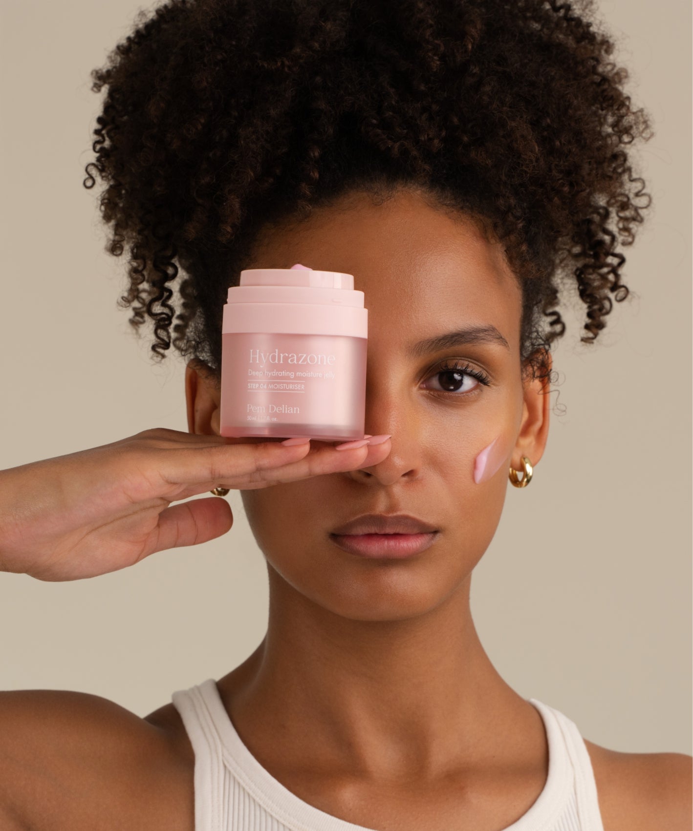 Pem Delian Hydrazone rózsaszínű arcápoló zselé tégely a modell kezén, textúra az arcon 