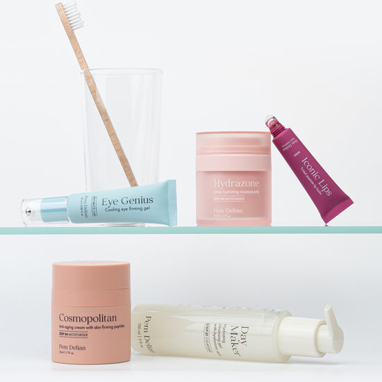 Pem Delian Hydrazone arckrém egy üveg polcon, mellette különböző fajta termékek és egy pohár, benne fogkefe