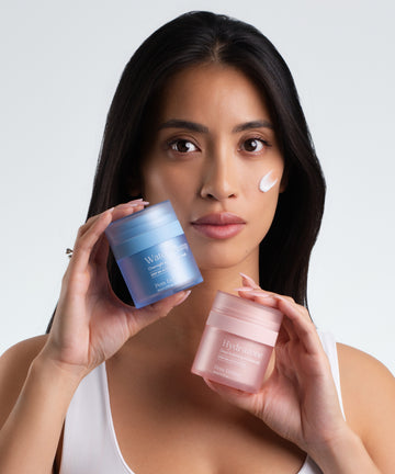 Pem Delian Water Plump és Hydrazone hidratálókat tart a modell a kezében, a krém textúrája kikenve az arcára