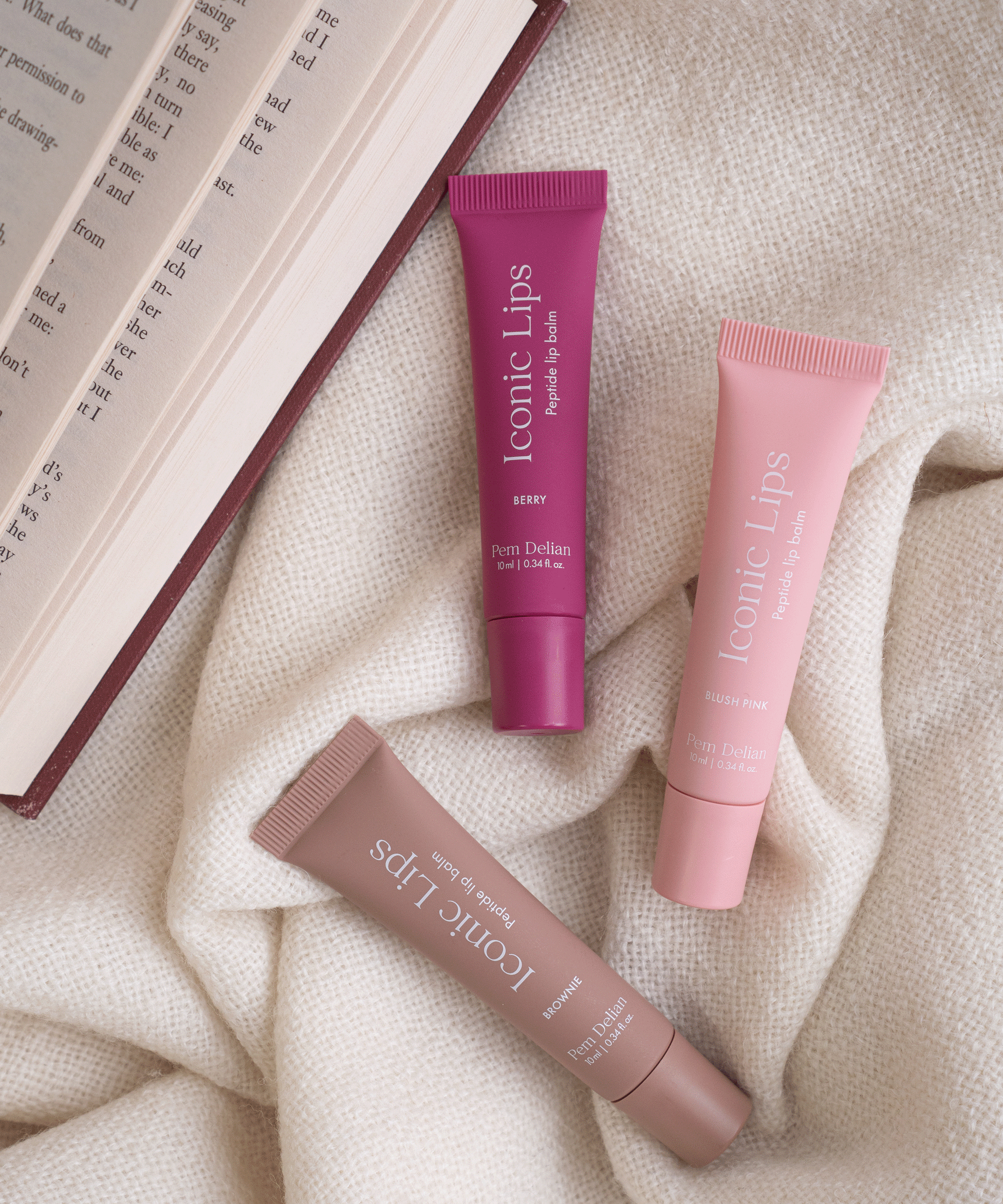 Iconic Lips berry, brownie, blush pink színezett, peptides ajakápoló szövet háttéren, nyitott könyv mellett