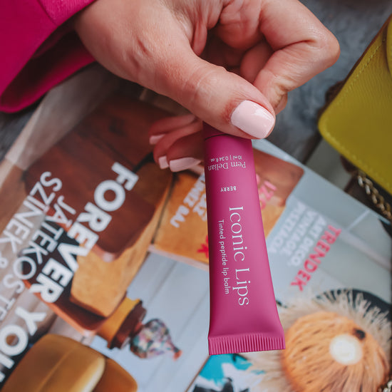 Iconic Lips berry színezett peptides ajakápoló modell kezében, magazin háttér előtt