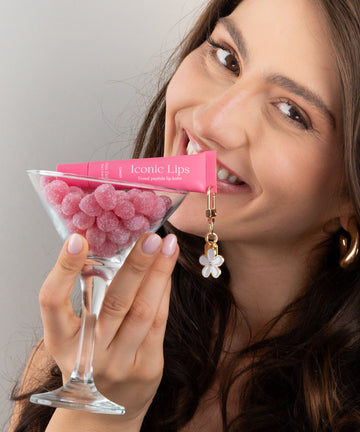 Pem Delian Iconic Lips candy színezett, peptides ajakápoló virágos charmmal
pohárban cukorkákkal barna hajú modell kezében