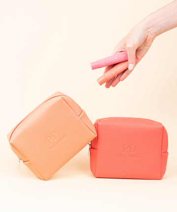 Pem Delian Iconic Lips coral és candy színezett, peptides ajakápoló modell kezében, plusz barack és korall színű neszeszer