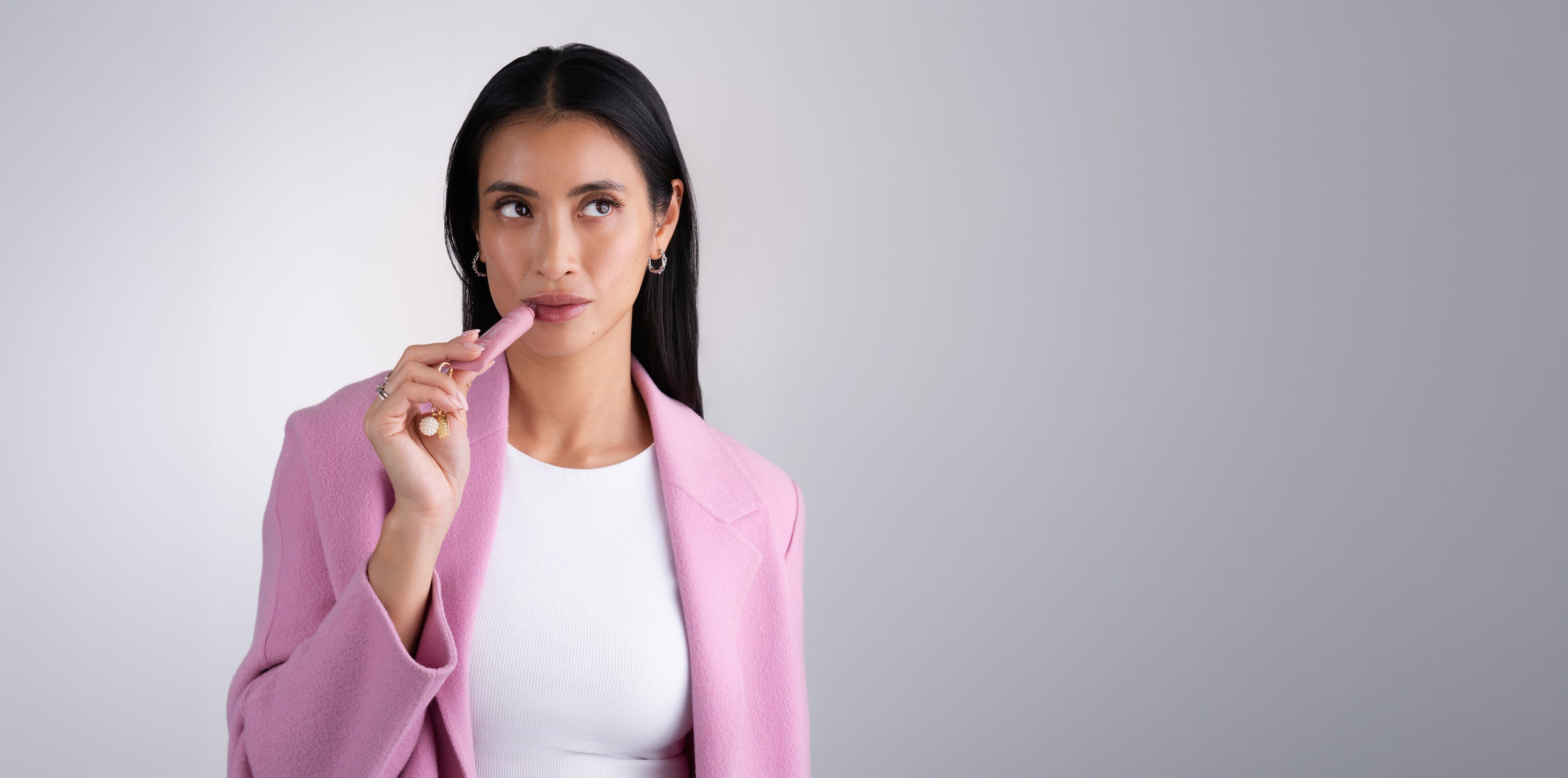 Pem Delian Iconic Lips Macaron ajakápoló modell kezében tartva ahogy a szájára applikálja 