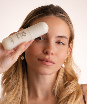 Pem Delian Milky Glow toner a modell kezében tartva ahogy a kamerába néz fehér háttér előtt 