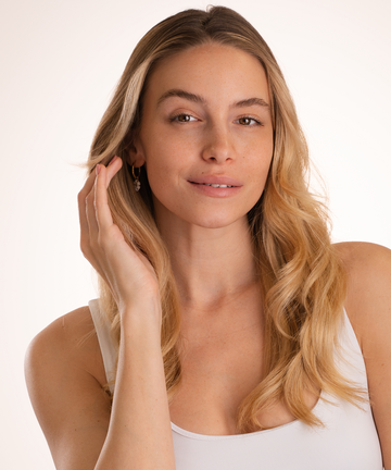 Pem Delian modell haját igazítja fehér háttér előtt állva