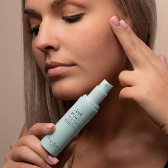 Pem Delian Peel Power AHA-BHA hámlasztó modell kezében, arc előtt tartva, ujjaival a terméket az arcán keni el 