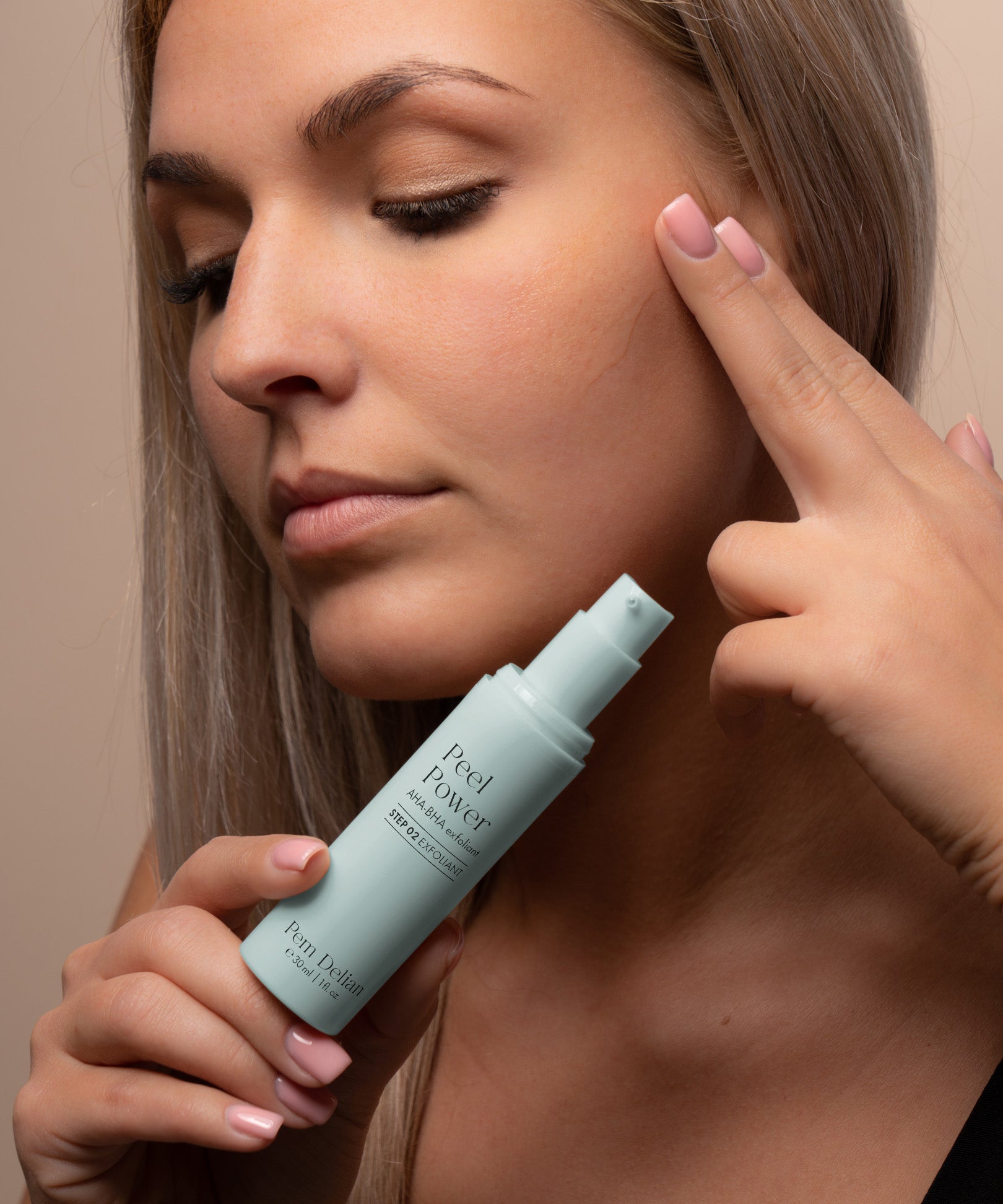 Pem Delian Peel Power AHA-BHA hámlasztó modell kezében, arc előtt tartva, ujjaival a terméket az arcán keni el 