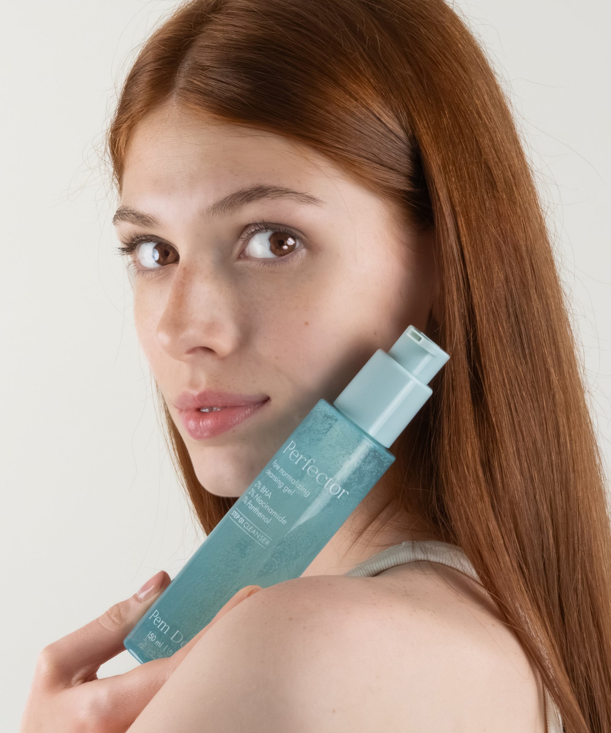 Pem Delian Perfector pórusnormalizáló arctisztító gél modell kezében tartva arc előtt