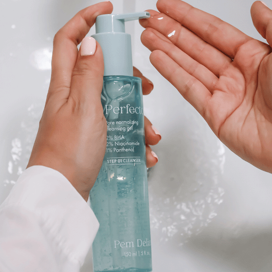 Pem Delian Perfector pórusnormalizáló arctisztító gél modell kezében tartva, kinyomva, csap felett