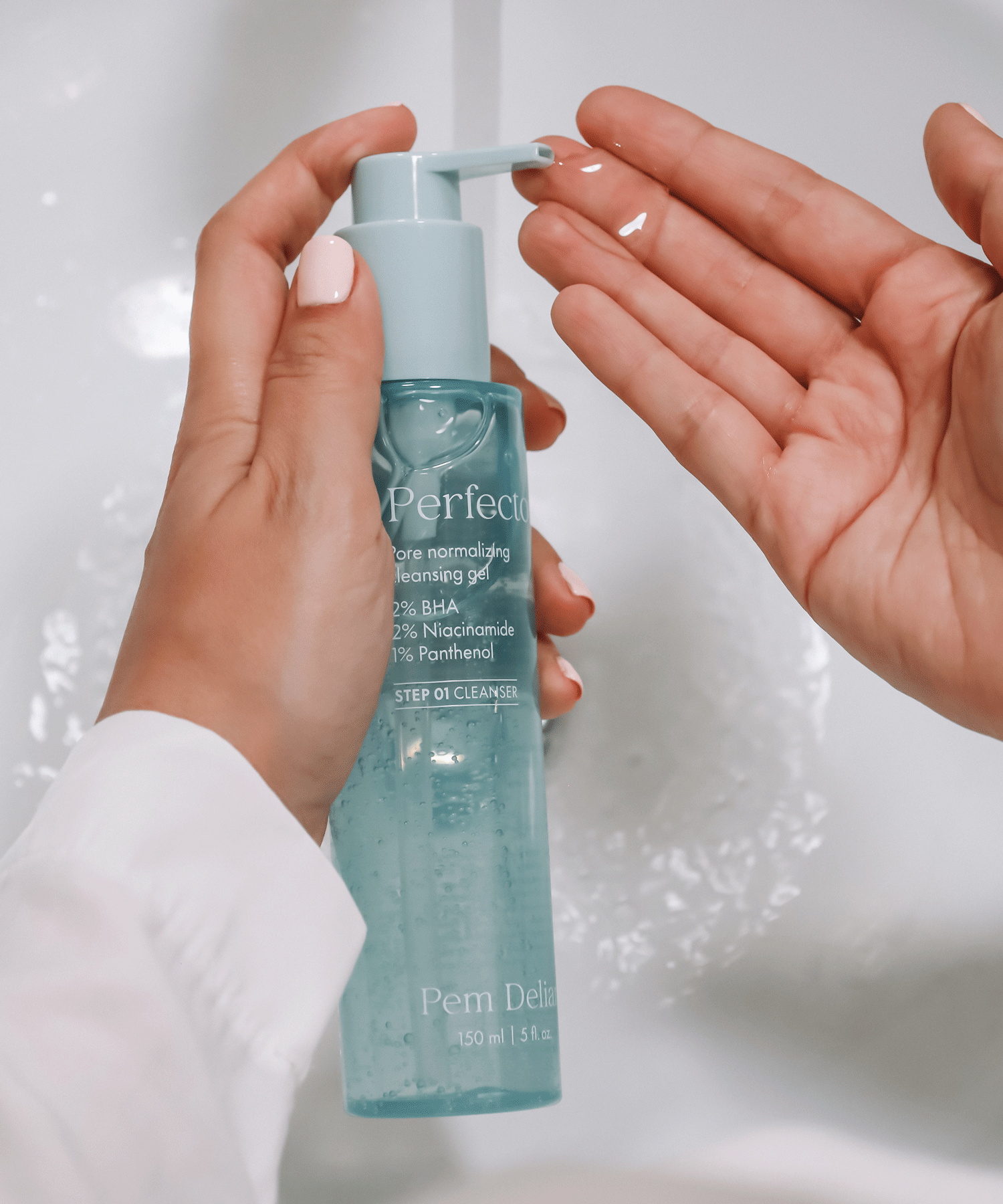 Pem Delian Perfector pórusnormalizáló arctisztító gél modell kezében tartva, kinyomva, csap felett