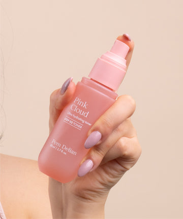 Pem Delian Pink Cloud NMF & Glycoin Ultra hidratáló toner modell kezében tartva, ujja a permetező fejen 