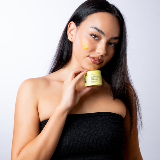 Pem Delian Restart Enzim + AHA-BHA hámlasztó gélmaszk barna hajú modell álla alatt tartva, a géles sárga textúra az arcára kikenve