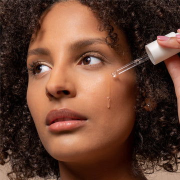 Pem Delian szérum pipetta barna szemű lány arca mellett, a termék kicseppen a pipettából