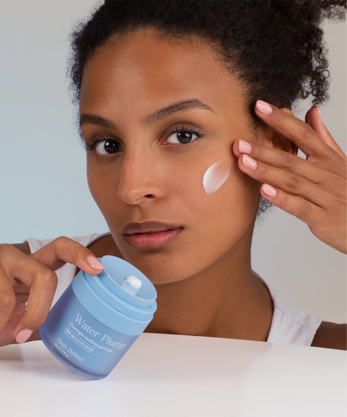 Pem Delian Water Plump éjszakai bőrselymesítő gélmaszk peptiddel barna modell arcán kikenve, kezében tégely